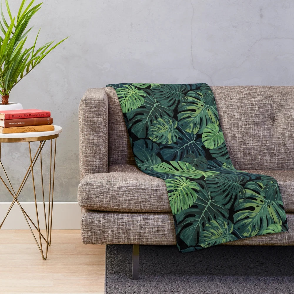 Lush green monstera leaves printed on a cozy plush blanket for home decor