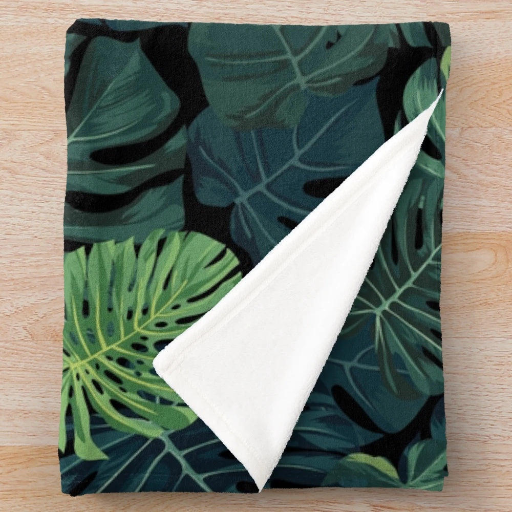 Lush green monstera leaves printed on a cozy plush blanket for home decor