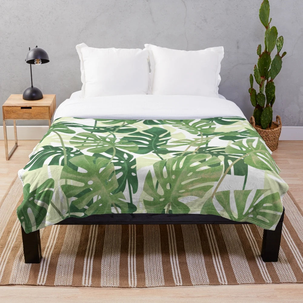 Lush, tropical monstera leaves printed on a cozy plush blanket