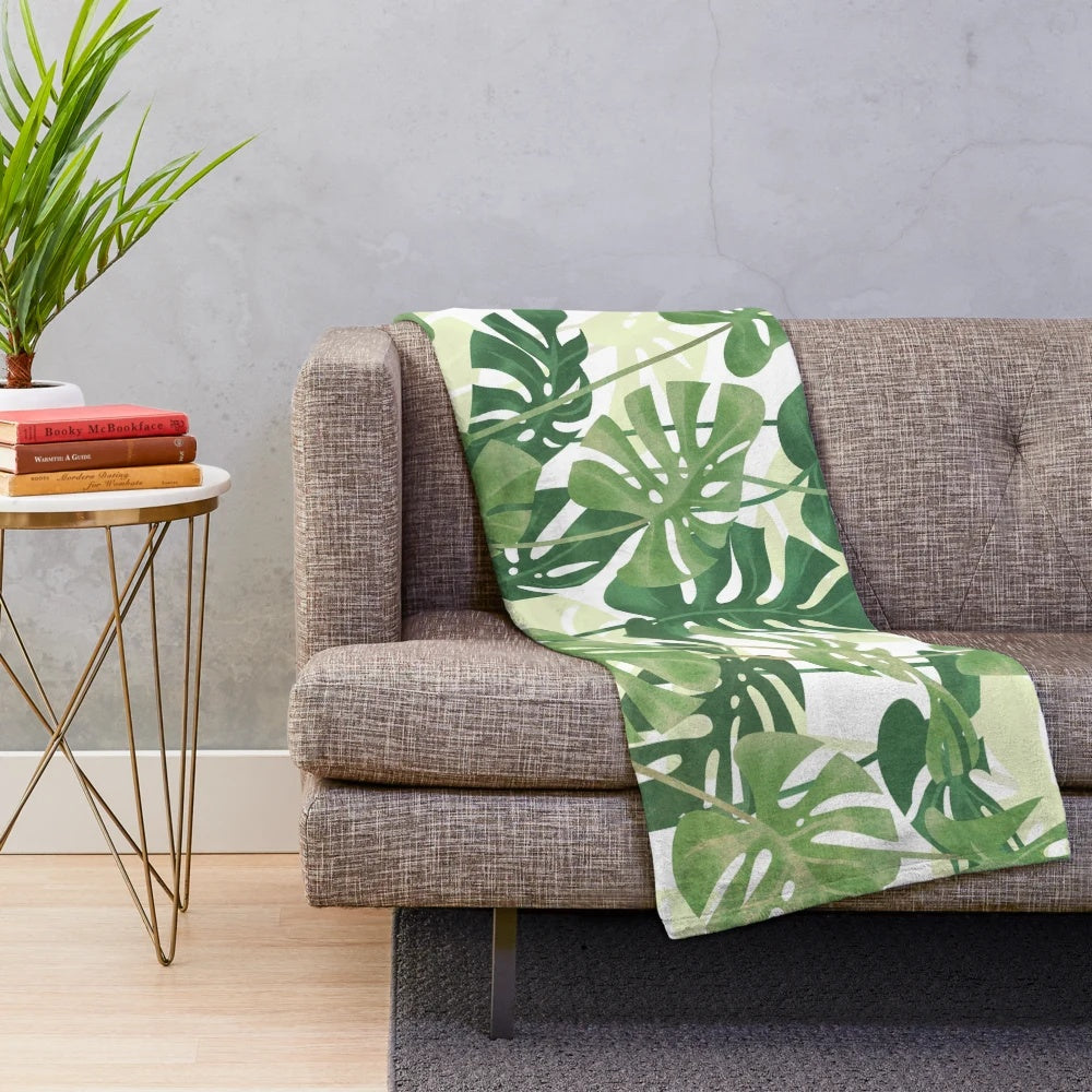 Lush, tropical monstera leaves printed on a cozy plush blanket