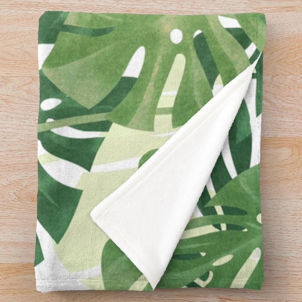 Lush, tropical monstera leaves printed on a cozy plush blanket