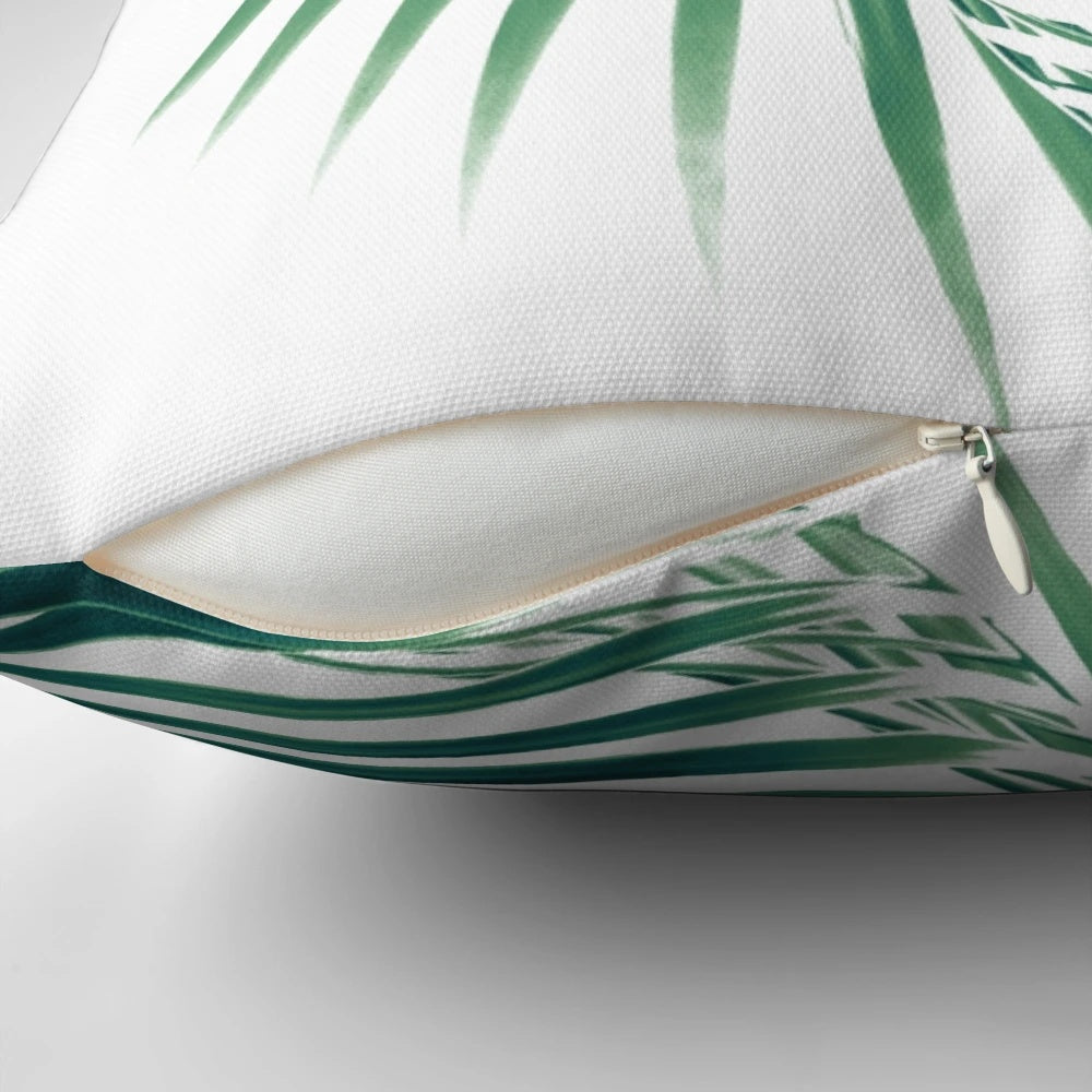Decorative pillow featuring a digital art design of tropical palm leaves in shades of green on a white background.