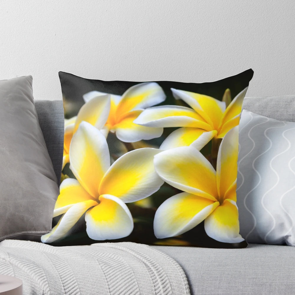 Vibrant yellow plumeria or frangipani flowers on a tropical floral pillow