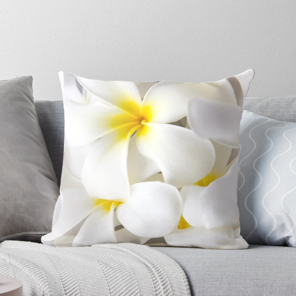 A throw pillow featuring a high-key close-up photograph of white plumeria or frangipani tropical flowers