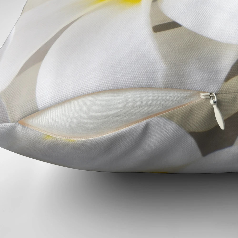 A throw pillow featuring a high-key close-up photograph of white plumeria or frangipani tropical flowers