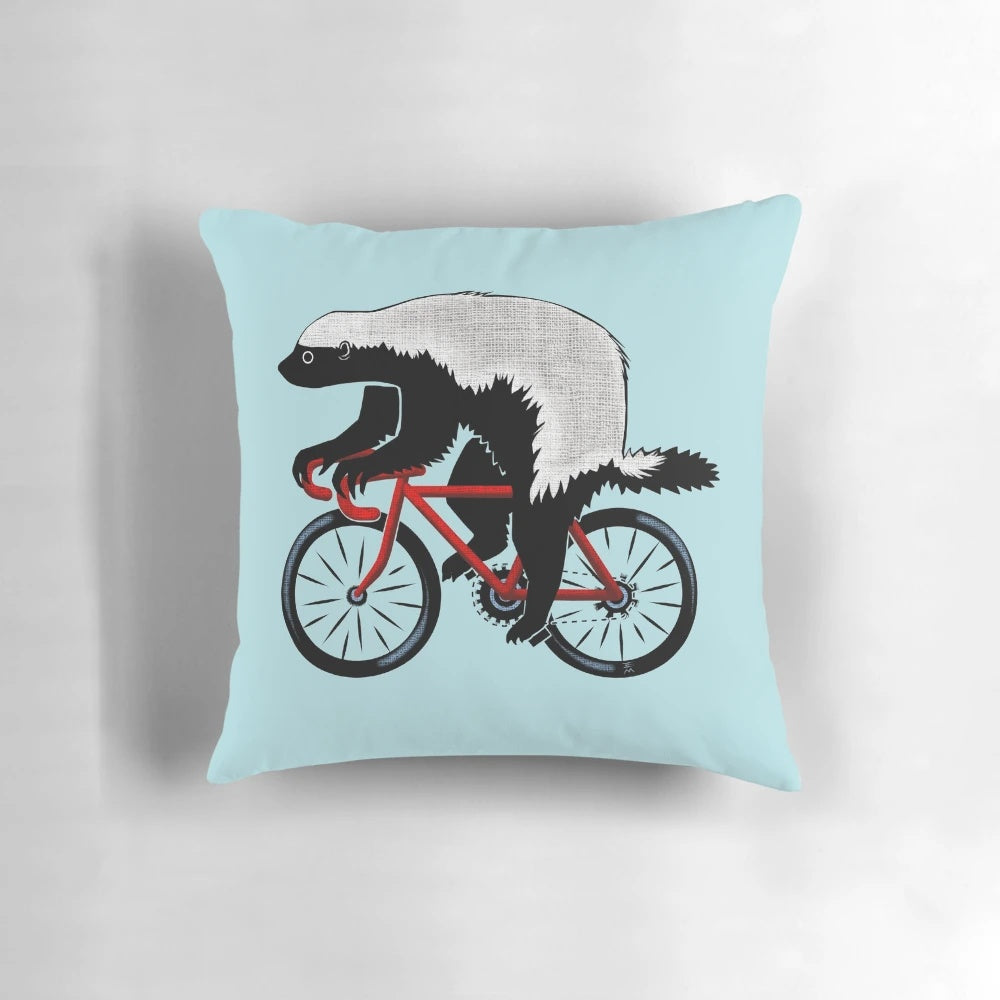 Honey badger riding a bicycle on a decorative throw pillow