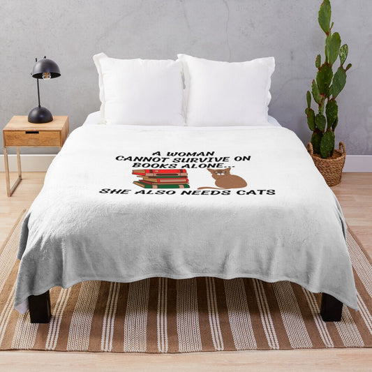 Plush blanket with text "A WOMAN CANNOT SURVIVE ON BOOKS ALONE SHE ALSO NEEDS CATS"