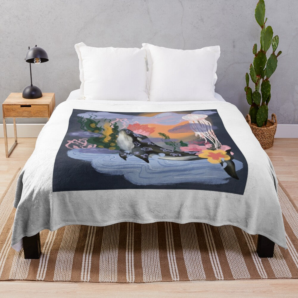 A plush blanket featuring a whimsical underwater scene with a whale, fish, and coral design