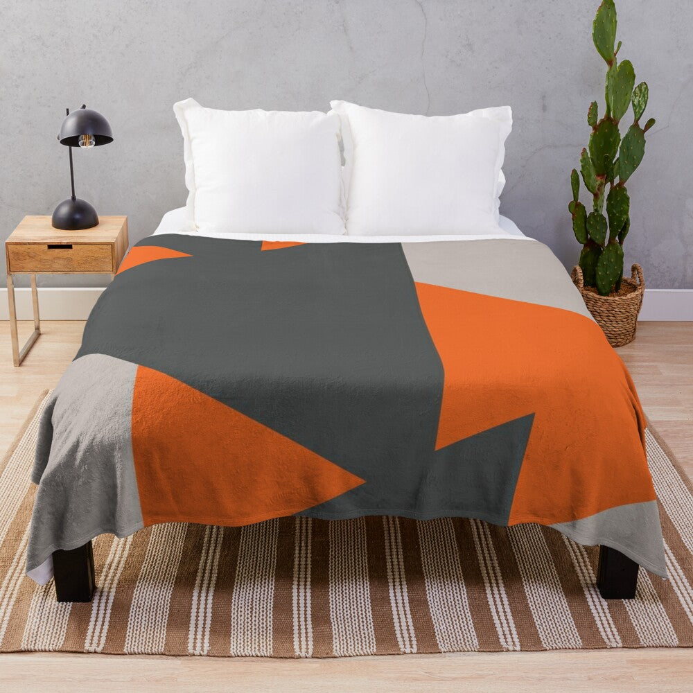 Cozy plush blanket featuring a geometric triangle pattern in orange and grey