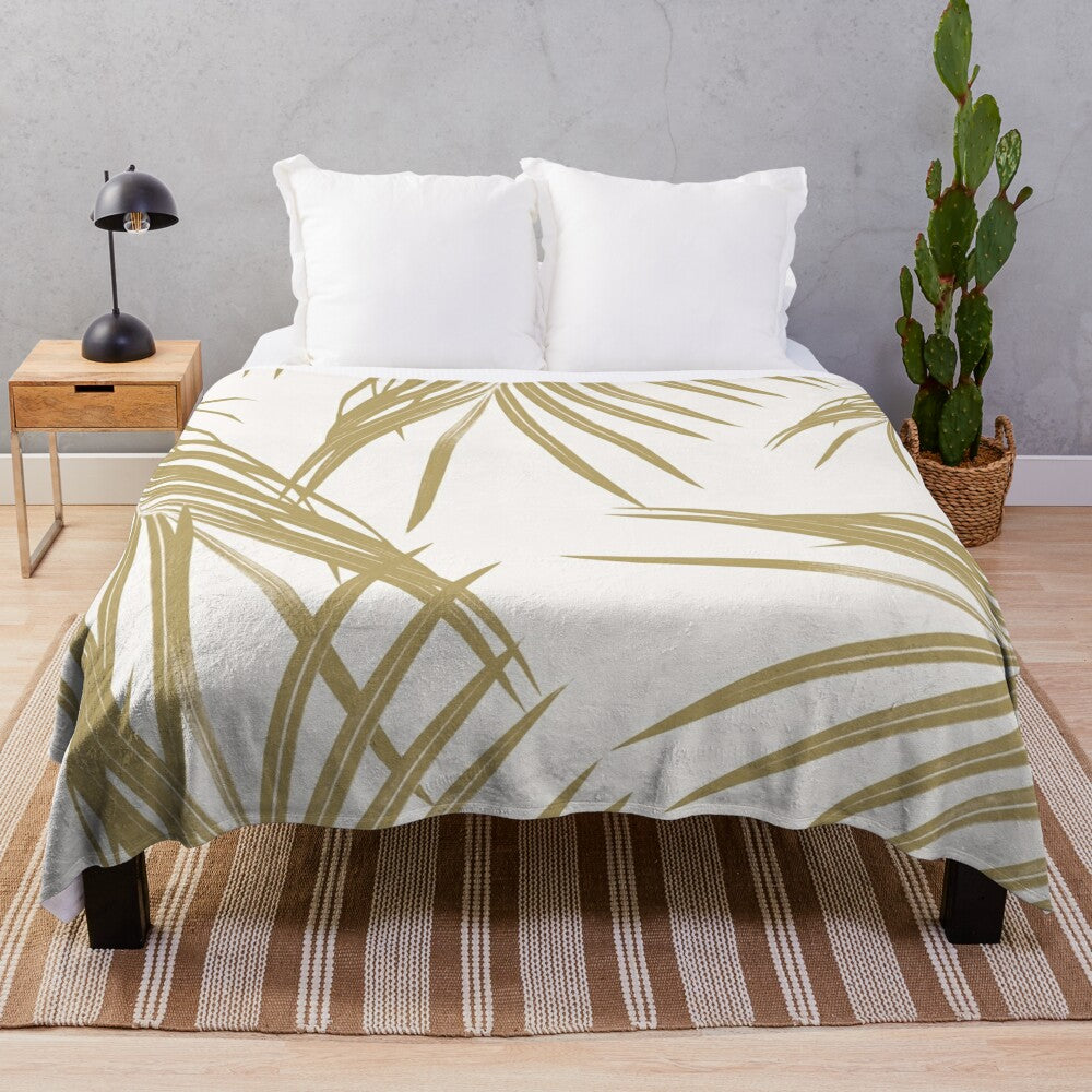 Plush blanket featuring a digital collage of gold palm leaves in a tropical design