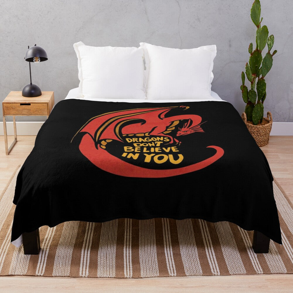 A plush red dragon-themed blanket with the text "Dragons don't believe in you"