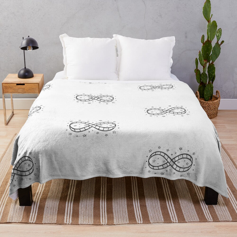 Plush blanket featuring a minimalist sketch illustration of an infinity symbol made from a movie film reel