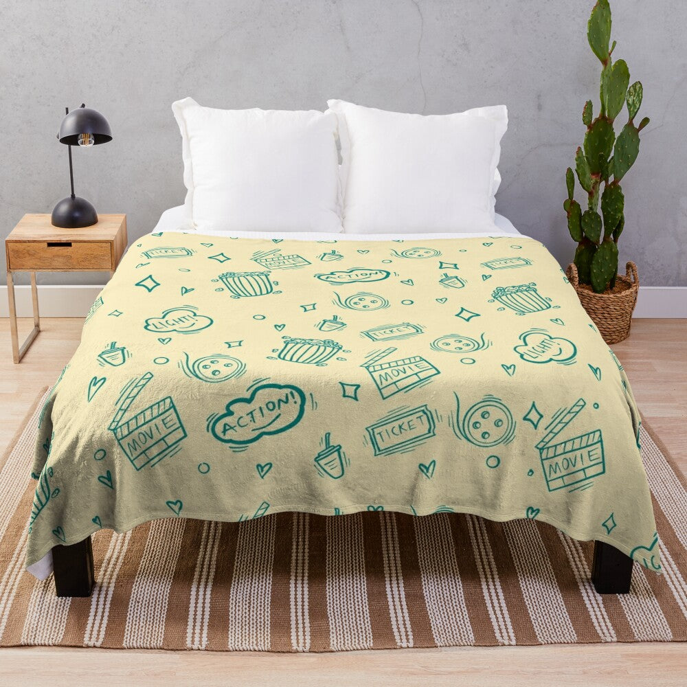 Plush blanket with a cinema-themed pattern featuring movie elements like popcorn, cameras, and retro drinks.