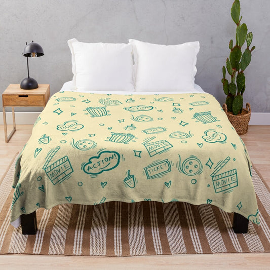 Plush blanket with a cinema-themed pattern featuring movie elements like popcorn, cameras, and retro drinks.