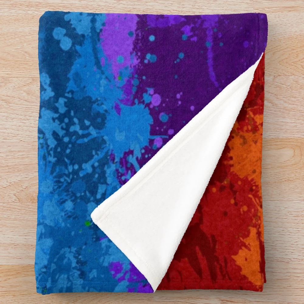 Colorful abstract paint splatter pattern on a plush blanket