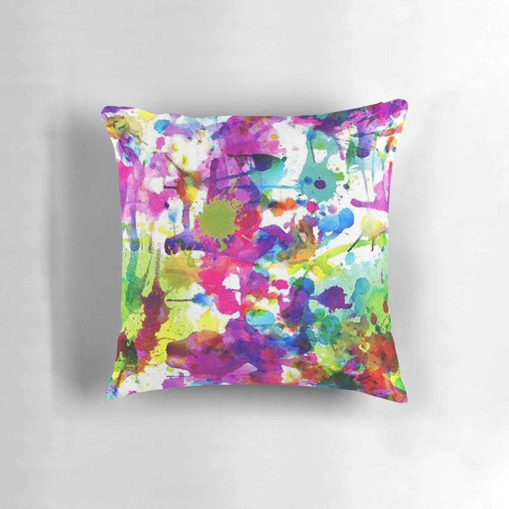 Bright and colorful abstract paint splatter design on a soft, modern throw pillow.