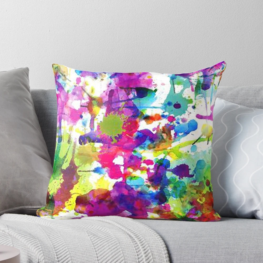 Bright and colorful abstract paint splatter design on a soft, modern throw pillow.