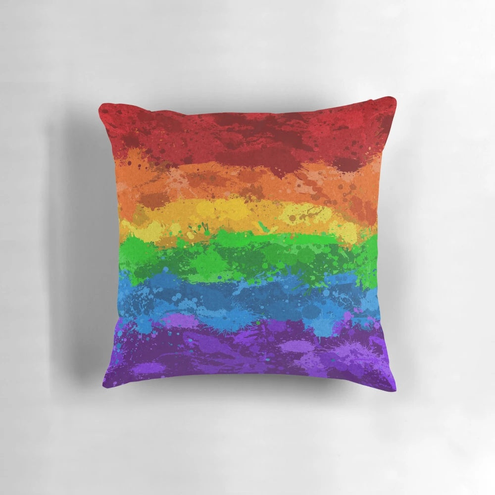 Colorful abstract paint splatter pattern in LGBTQ pride colors on a pillow.