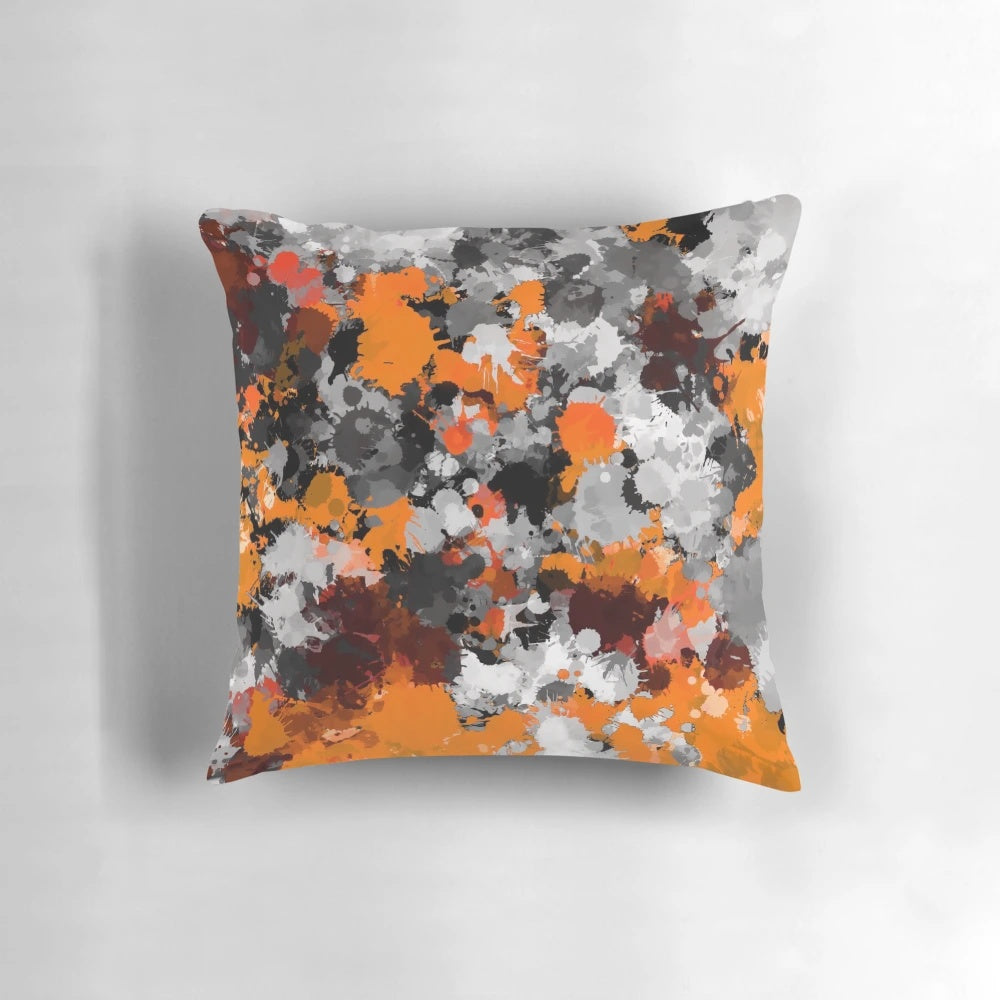 Orange and grey paint splatter design on a square throw pillow