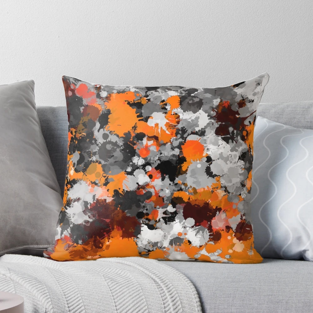 Orange and grey paint splatter design on a square throw pillow