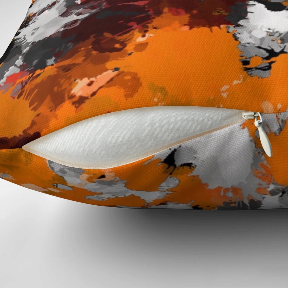 Orange and grey paint splatter design on a square throw pillow