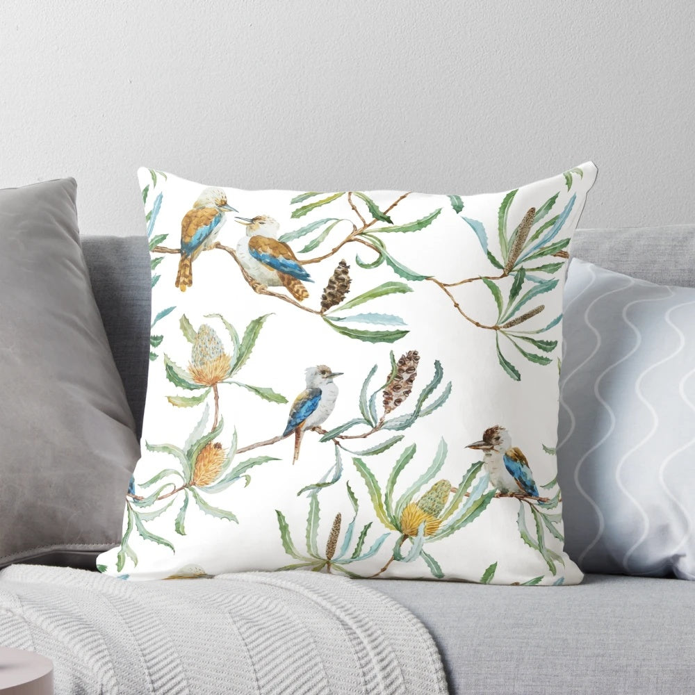 A decorative throw pillow featuring a bright and colorful pattern of Australian kookaburras, yellow waratah flowers, and green leaves on a white background.