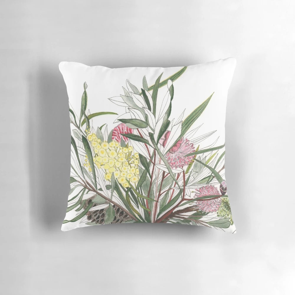 Colorful watercolor-inspired bouquet of Australian native flowers like banksia, grevillea, and wattle on a throw pillow.
