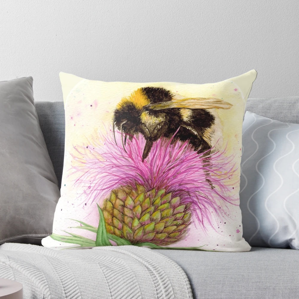 Closeup of a beautiful watercolor painting of a bee perched on a purple thistle flower, presented on a decorative throw pillow.