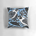 A beautiful throw pillow featuring a linocut-inspired image of blue birds perched on a tree branch with flowers and leaves.