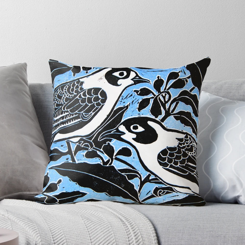 A beautiful throw pillow featuring a linocut-inspired image of blue birds perched on a tree branch with flowers and leaves.