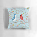 A colorful throw pillow featuring a seamless pattern of blue jays and red cardinals perched on tree twigs.
