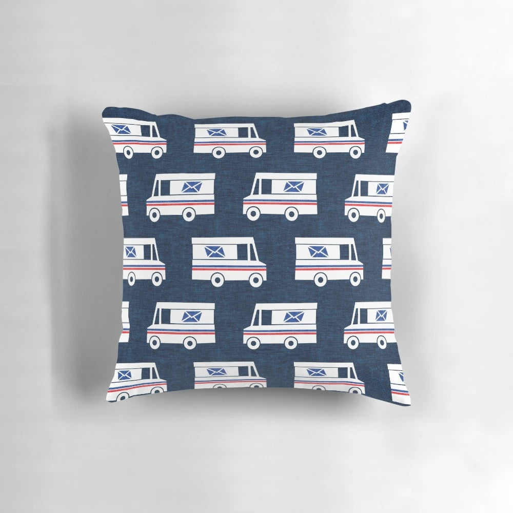 Closeup of a blue pillow with a mail truck and little arrow design printed on it