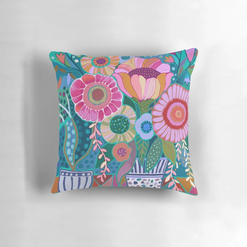Exuberant flowers in blue, green, pink, and yellow vases printed on a decorative throw pillow.
