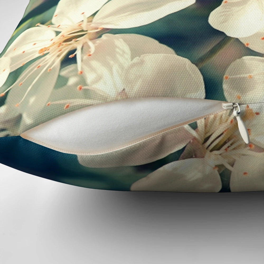 A soft, decorative pillow featuring a close-up image of delicate pink cherry blossoms on a tree branch.