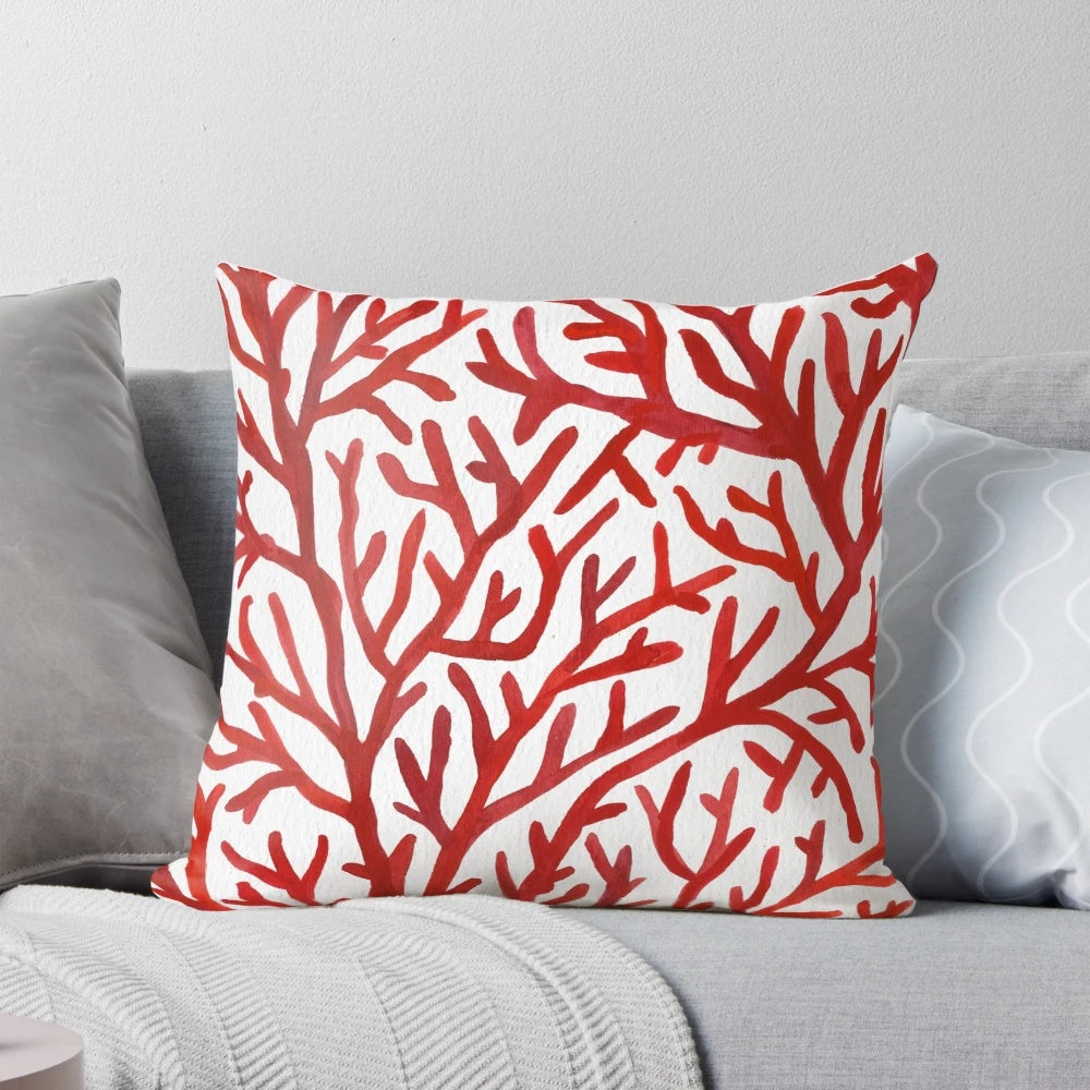 Red and gold watercolor coral design on a decorative throw pillow