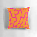 Preppy coral reef pattern in shades of pink and orange on a throw pillow