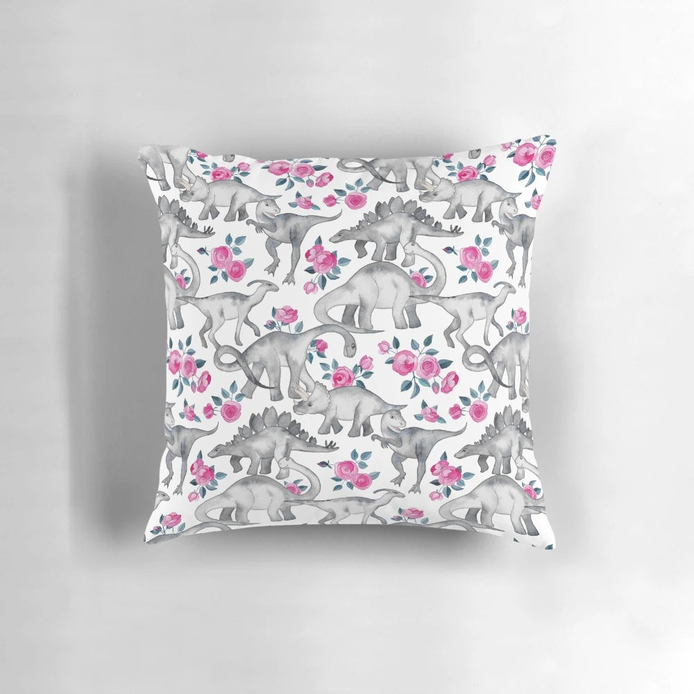 Pillow featuring a watercolor design of dinosaurs and roses in white, pink, and shades of green.