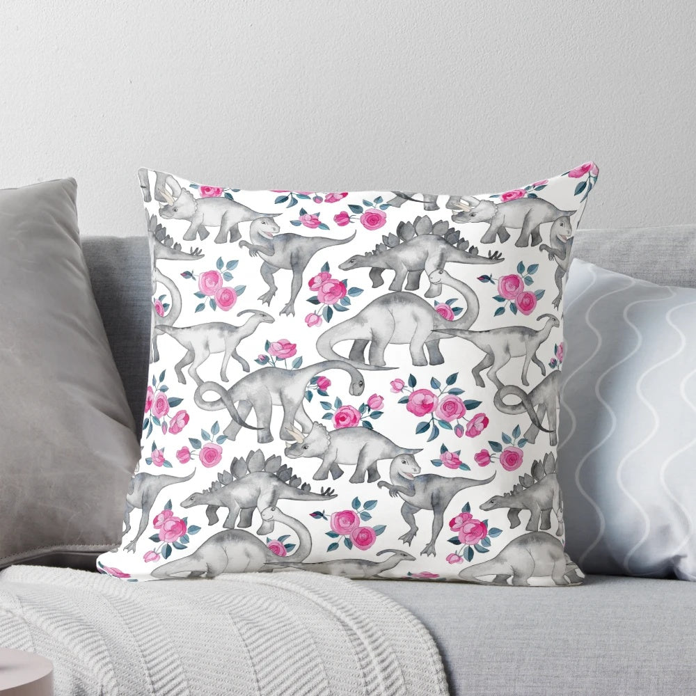 Pillow featuring a watercolor design of dinosaurs and roses in white, pink, and shades of green.