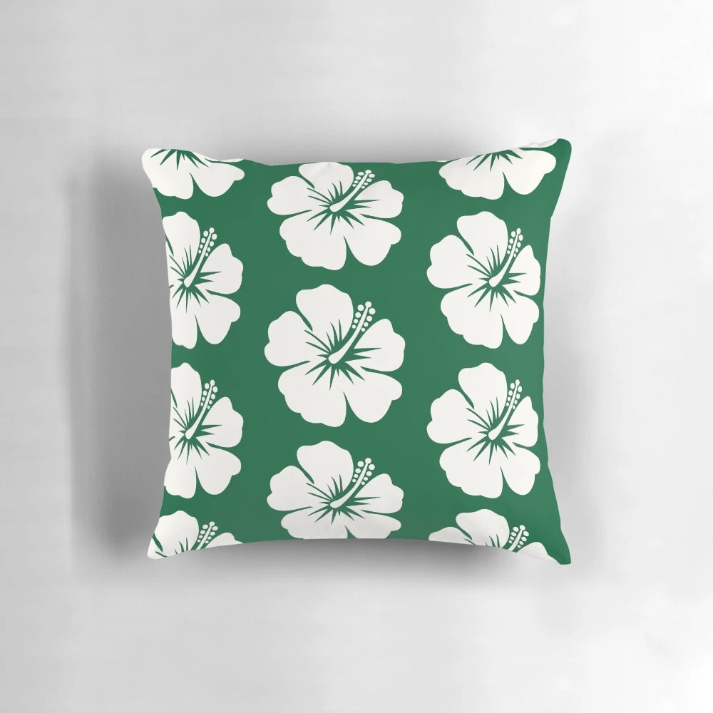 A forest green throw pillow with a bold hibiscus flower print in pastel colors.