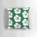 A forest green throw pillow with a bold hibiscus flower print in pastel colors.