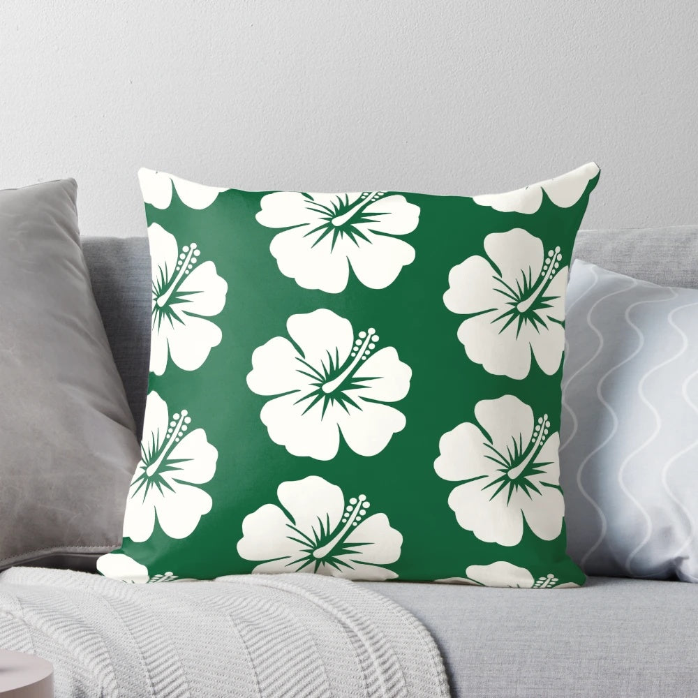 A forest green throw pillow with a bold hibiscus flower print in pastel colors.