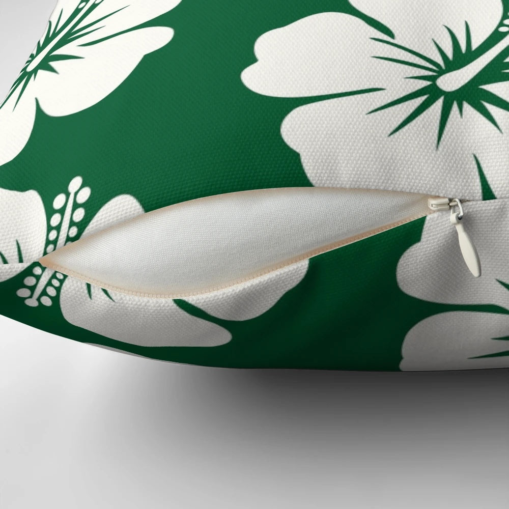 A forest green throw pillow with a bold hibiscus flower print in pastel colors.