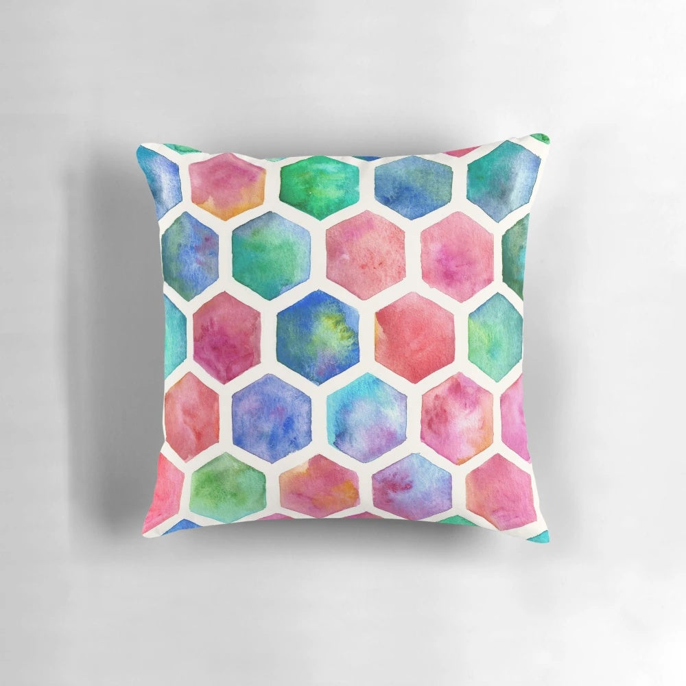 A colorful throw pillow featuring a hand-painted watercolor honeycomb pattern design in blue, red, green, pink, and purple tones.