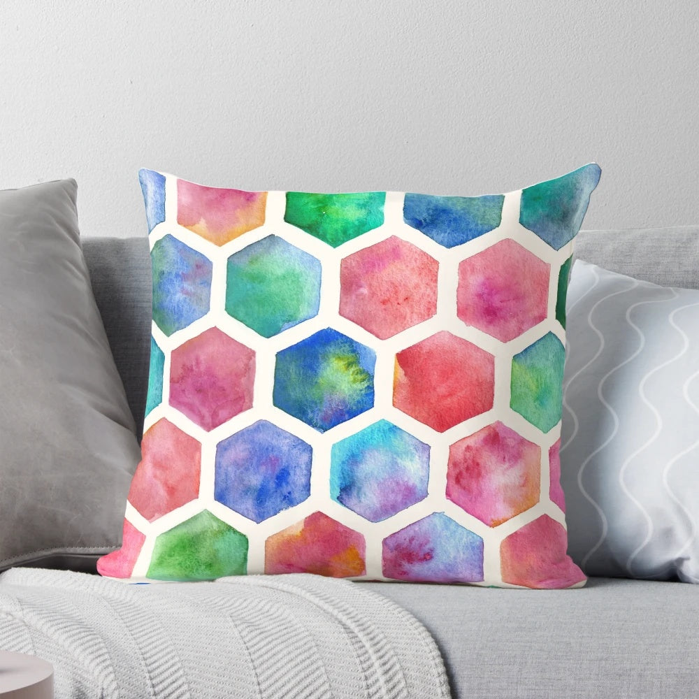 A colorful throw pillow featuring a hand-painted watercolor honeycomb pattern design in blue, red, green, pink, and purple tones.