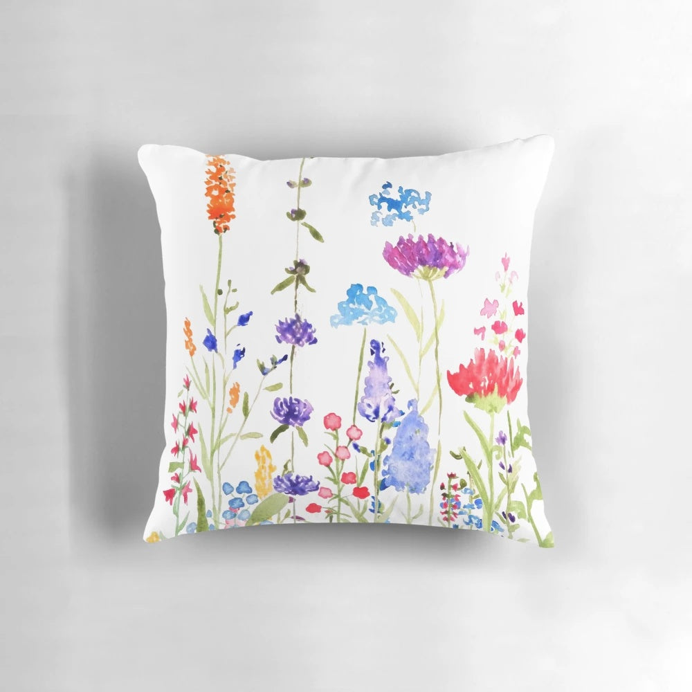 A colorful, hand-painted watercolor painting of wild, blooming wildflowers on a decorative pillow.
