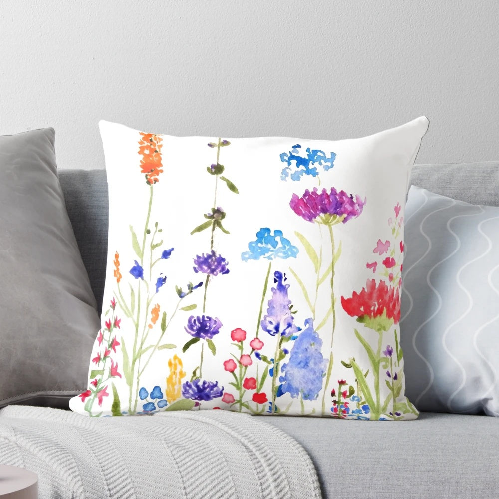 A colorful, hand-painted watercolor painting of wild, blooming wildflowers on a decorative pillow.
