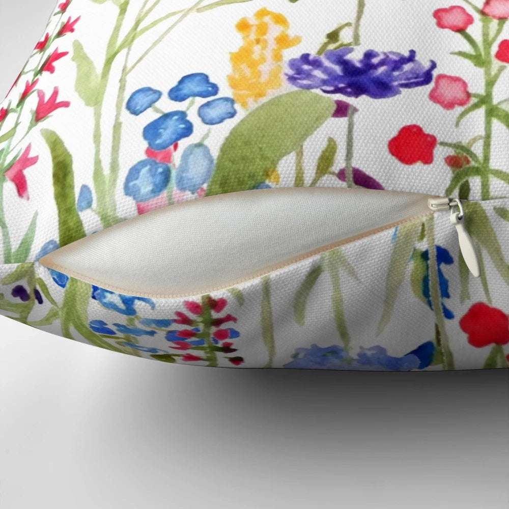 A colorful, hand-painted watercolor painting of wild, blooming wildflowers on a decorative pillow.