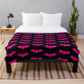 Plush blanket with a spooky bat tile pattern in hot pink and black