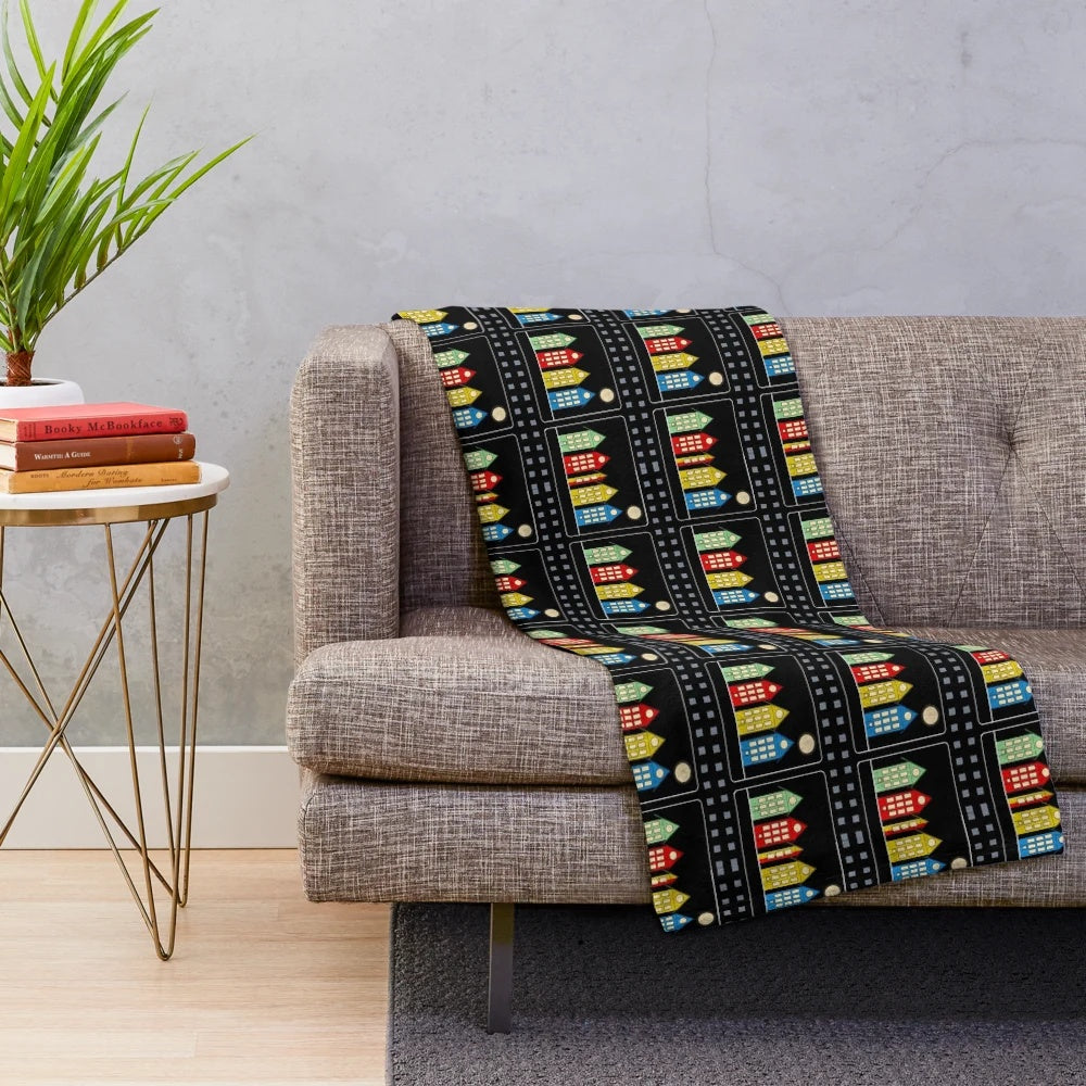 Colorful digital illustration of four houses and cinema with moon in night sky, depicted on a plush blanket