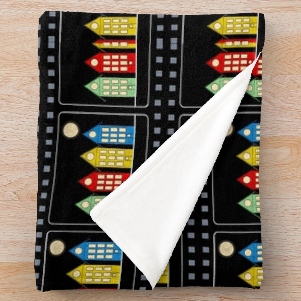 Colorful digital illustration of four houses and cinema with moon in night sky, depicted on a plush blanket